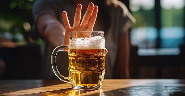 En hand gör stopptecken mot ett glas med öl
