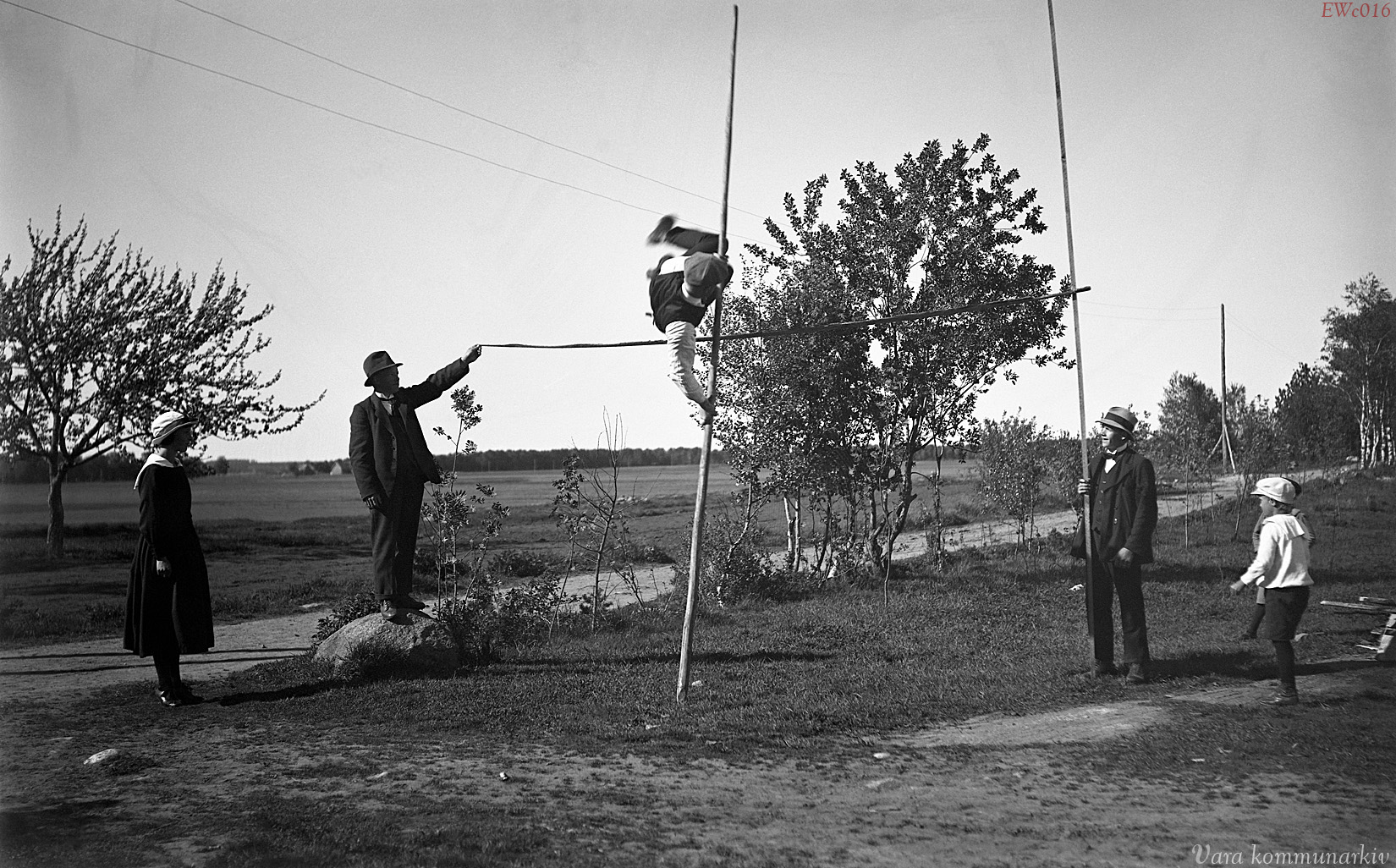 Svartvitt gammalt foto av man som hoppar stavhopp.