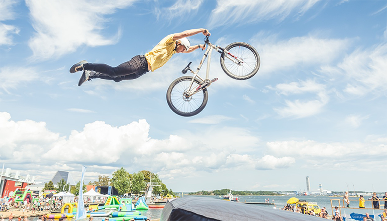 Hopp med cykel, högt upp i luften, mannen håller bara i styret och låter benen flyga fritt.