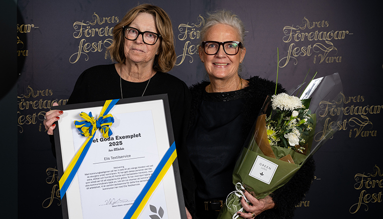 Två kvinnor med diplom och blommor i händerna.