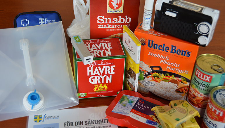 Olika matvaror, en vattendunk och en vevradio på ett bord.