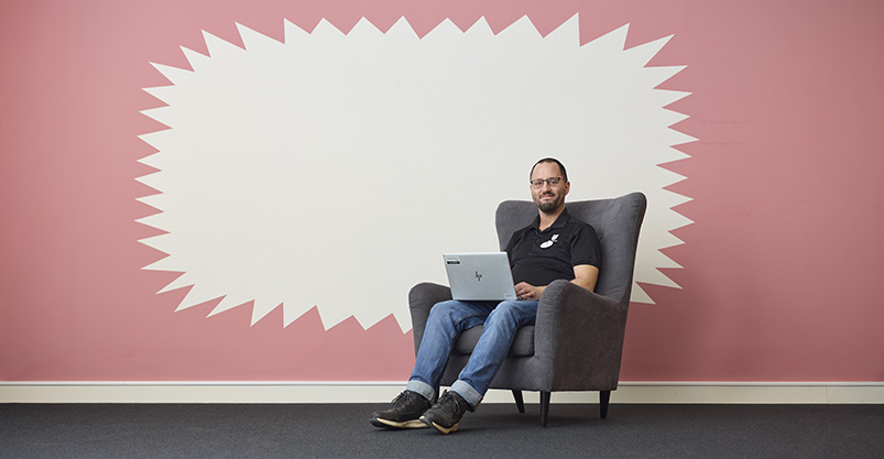 En man sitter i en fåtölj med en dator i knät