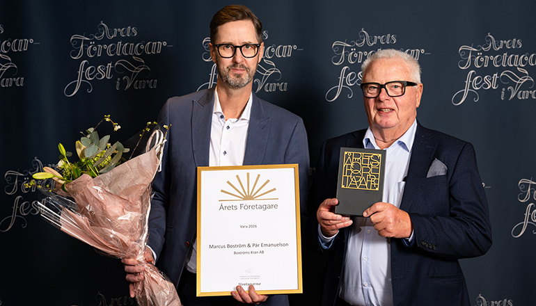 Två män med diplom och blommor.