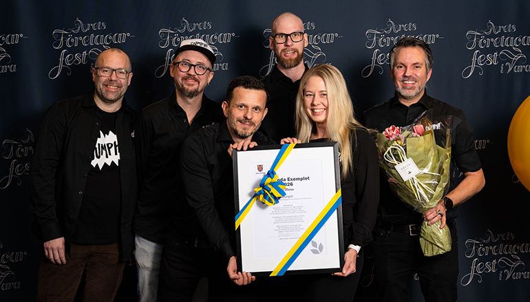 Fem män och en kvinna med diplom och blommor i händerna.