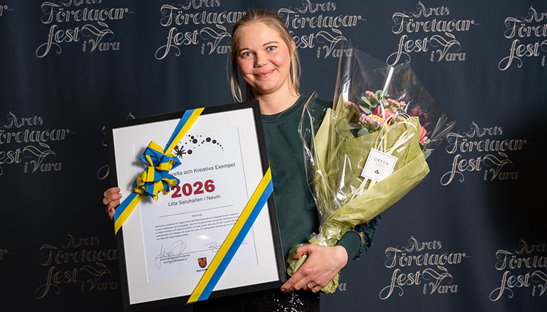 En kvinna med diplom och blommor i händerna.