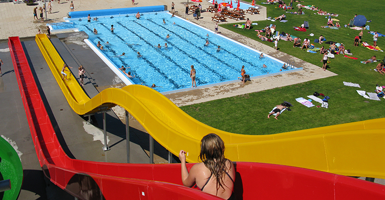 Tjej som sitter i en vattenrutschkana på utomhusbadet