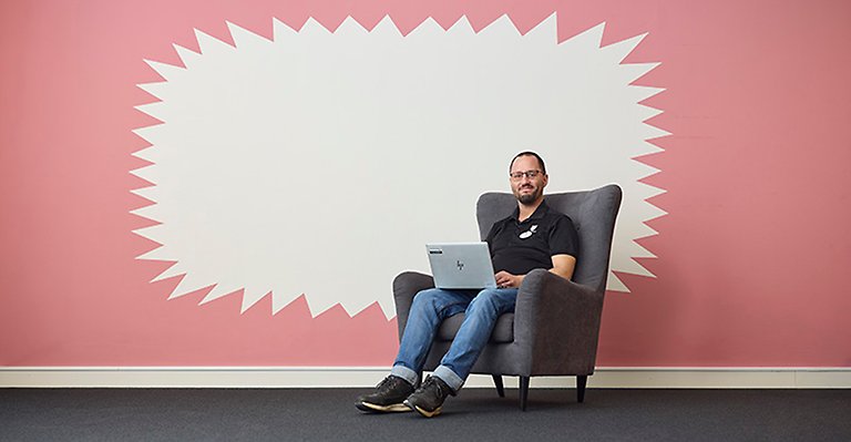 En man sitter i en fåtölj med en dator i knät